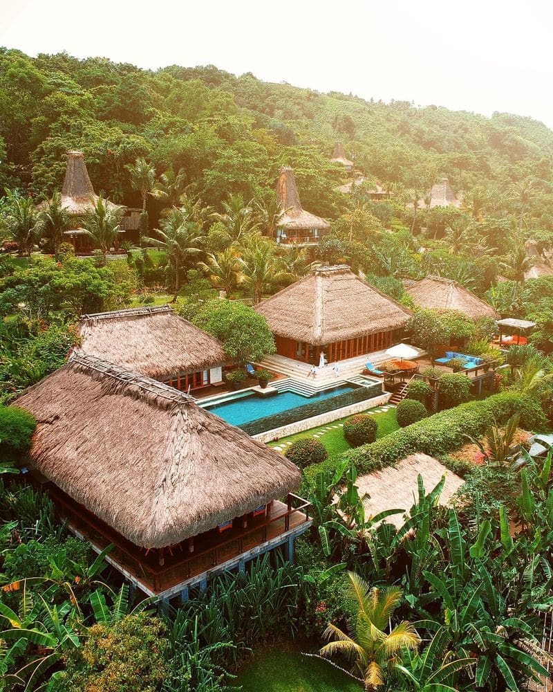Aerial view of thatched villas set into the jungle