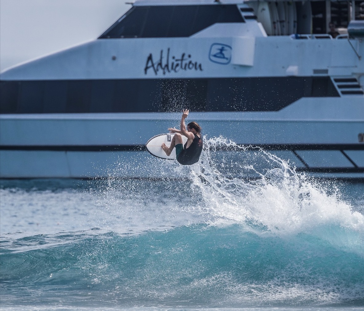 Surfer beside the MV Addiction charter boat