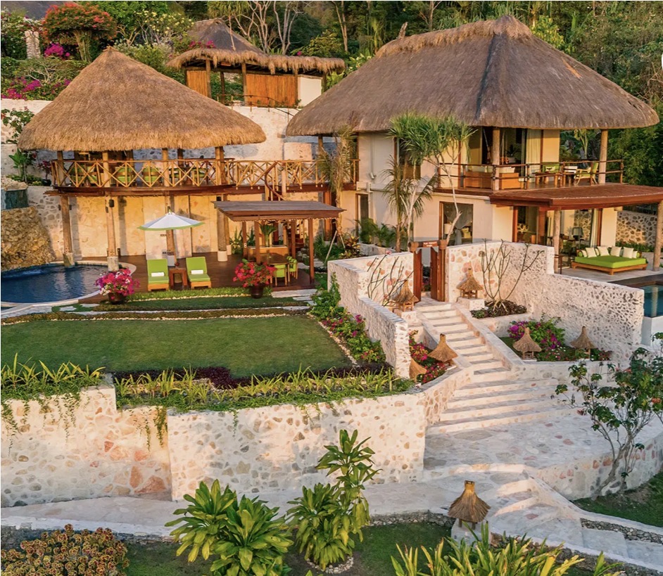 Putri Wamoro Jungle Villa with thatched roofs, stone walls, and garden pools