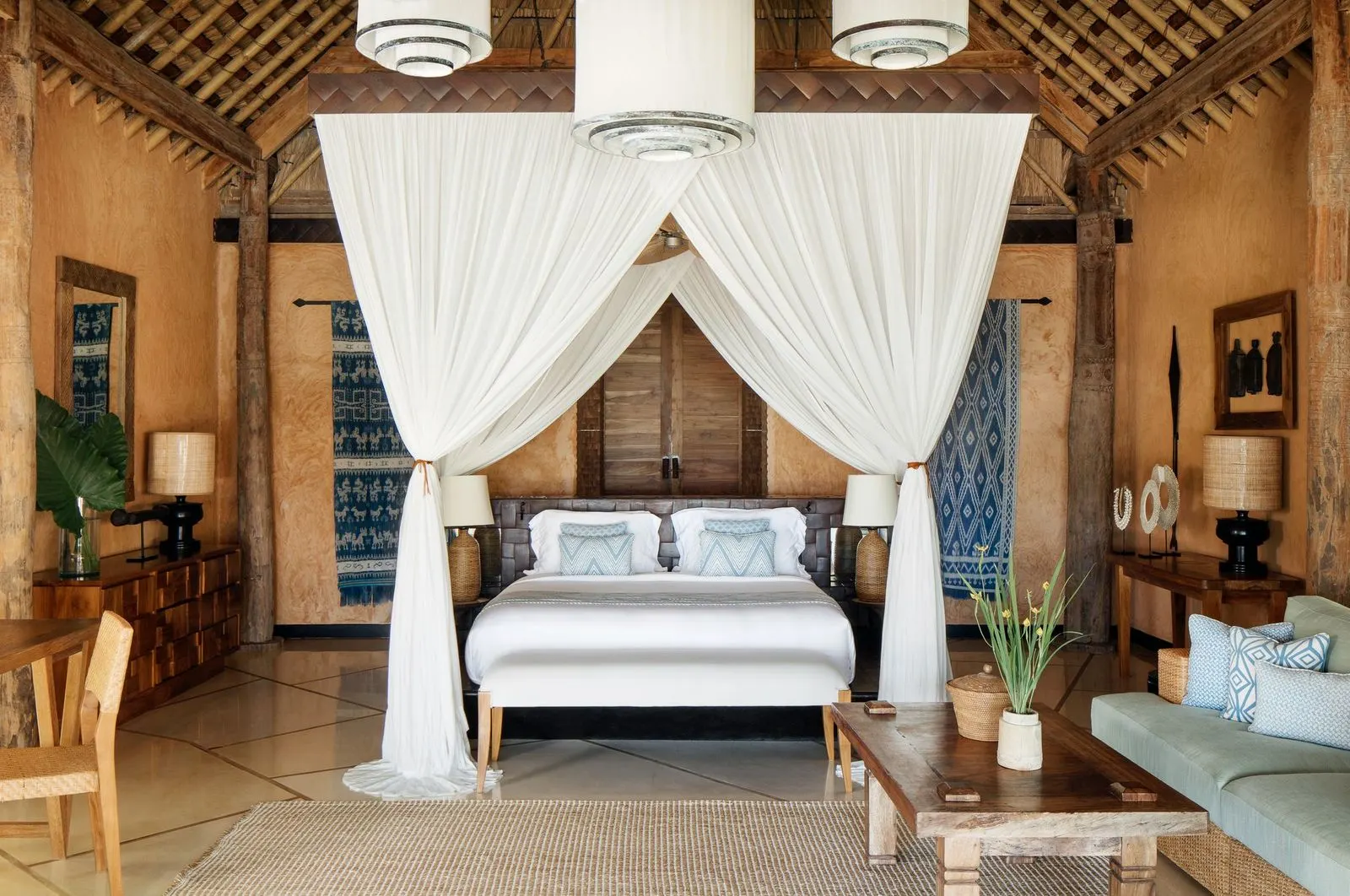 Four-poster canopy bed in a thatched villa with ikat textiles