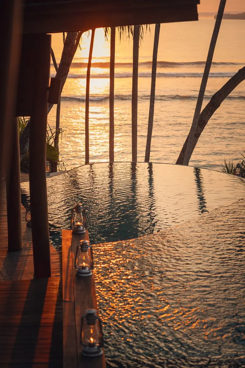 Sunset infinity pool with lanterns overlooking the surf at NIHI Sumba