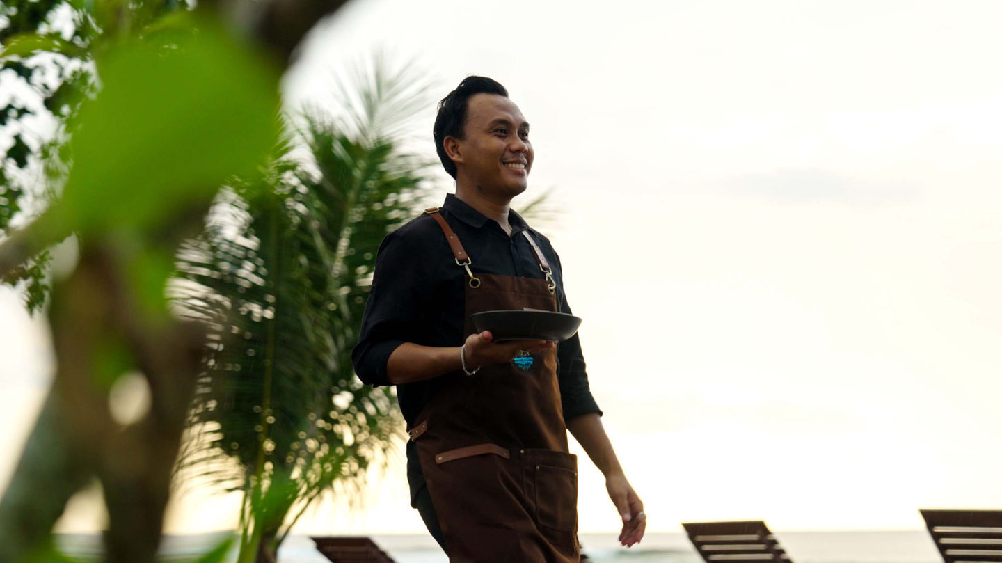 Staff serving a meal at the open-air beachfront restaurant